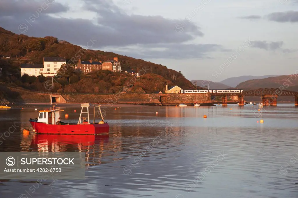 Wales, Gwynedd, Barmouth. Barmouth harbour and railway bridge - a train is crossing the bridge.