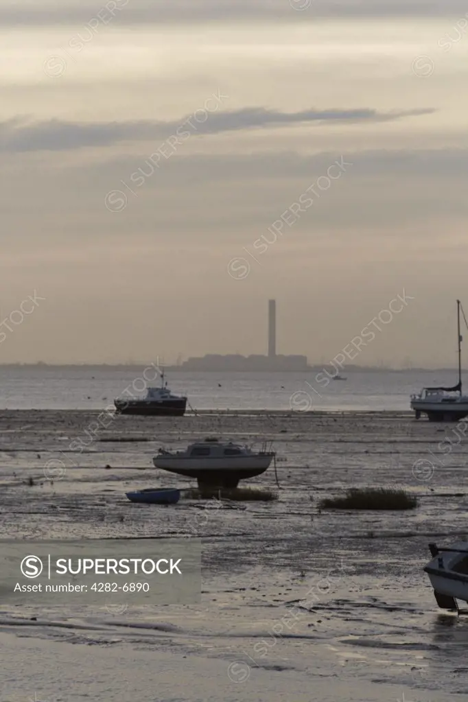 England, Essex, Leigh-on-Sea. Small boats moored in the estuary at Leigh-on-Sea in Essex with a factory in the far distance.