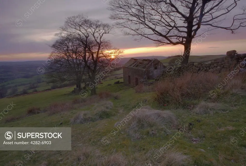 England, Staffordshire, Roach End. Sunset over a disused farm building at Roach End Farm in the Peak District.