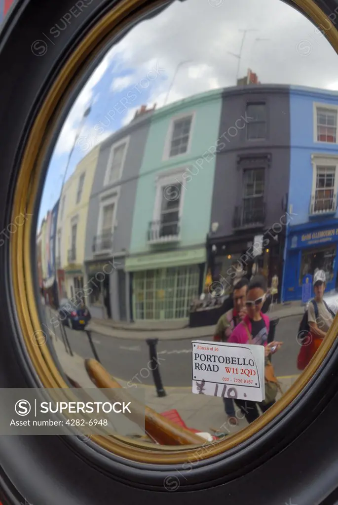 England, London, Notting Hill. Tourists reflected in an antique mirror for sale in Portobello road.