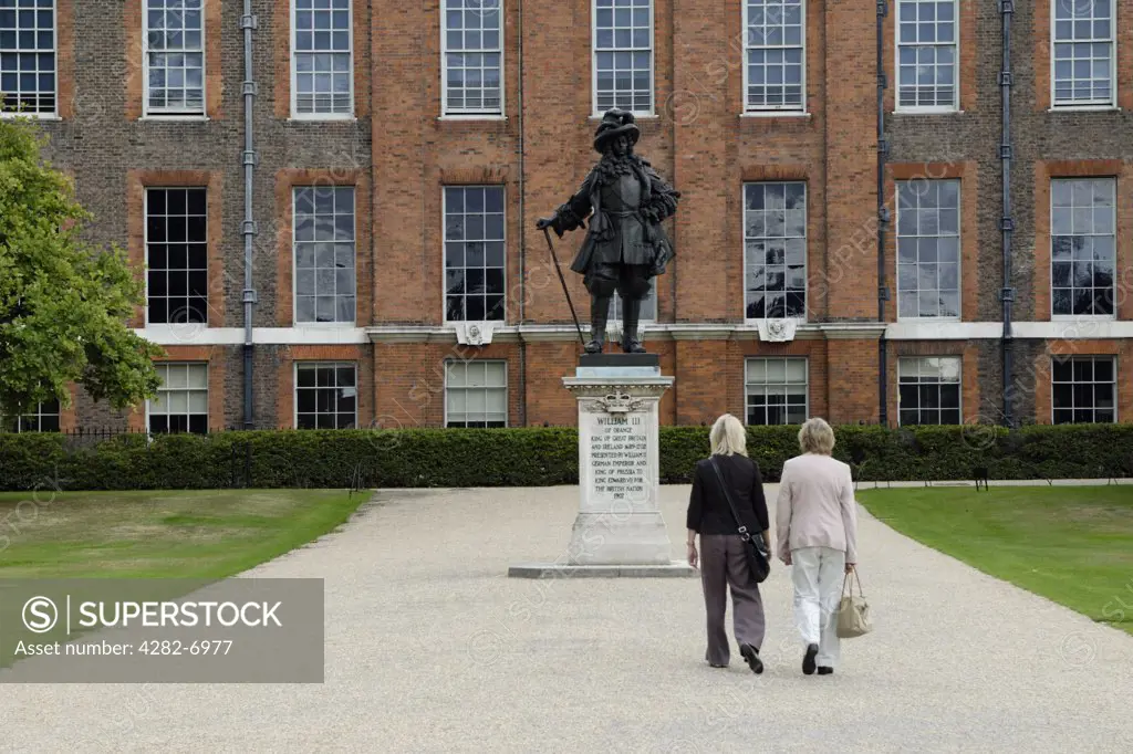 England, London, Kensington. Two tourists walking towards the statue of William III in front of Kensington Palace.