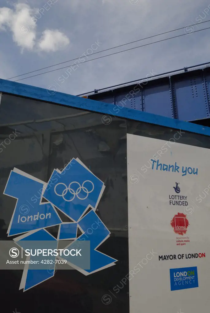 England, London, Stratford. The London 2012 Olympic logo displayed on hoardings outside the entrance of the construction site for the Olympic Village.