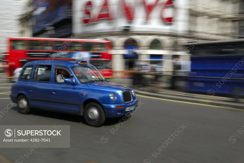 England, London, Piccadilly Circus. A London taxi hurrying past advertisements in Piccadilly Circus with a London double decker bus in the background.