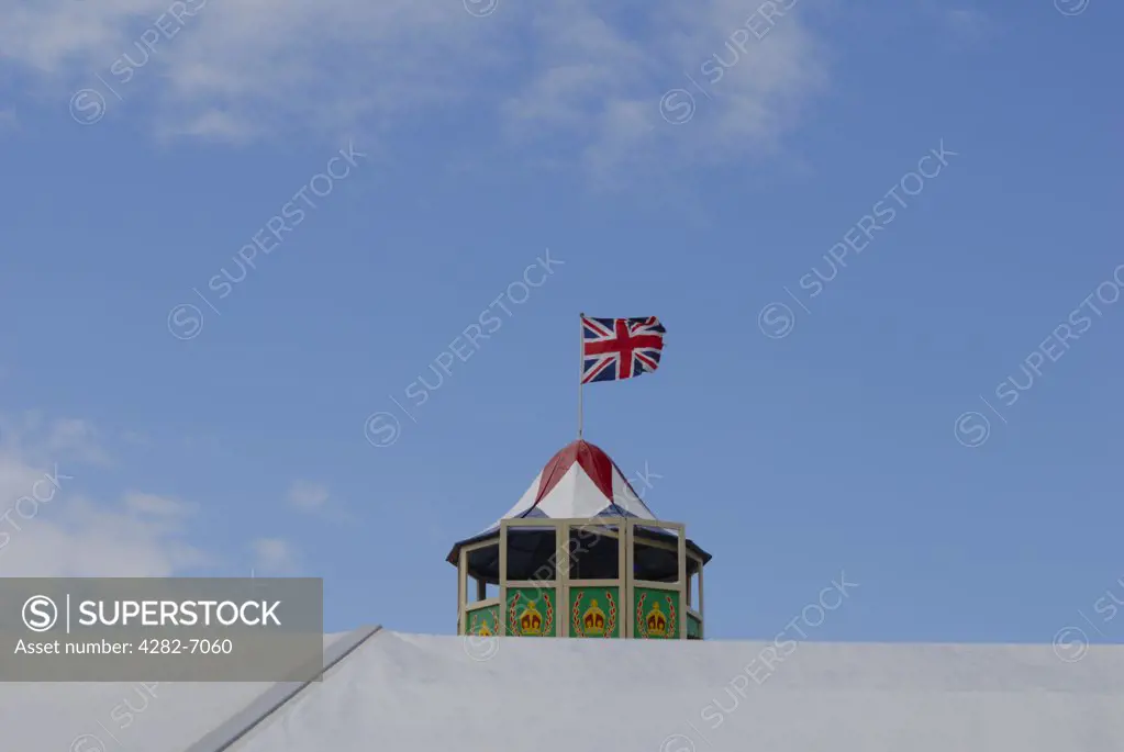 England, Kent, Detling. View across the top of a marquee to the top of a traditional helter skelter with the union jack flying on top at the kent Couty Show.