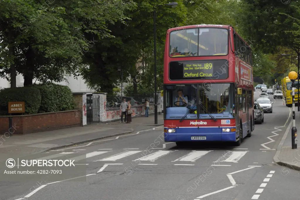 England, London, St John's Wood. A red London double decker bus stopped at the famous pedestrian crossing on Abbey Road which features on the cover of The Beatles album 'Abbey Road'.