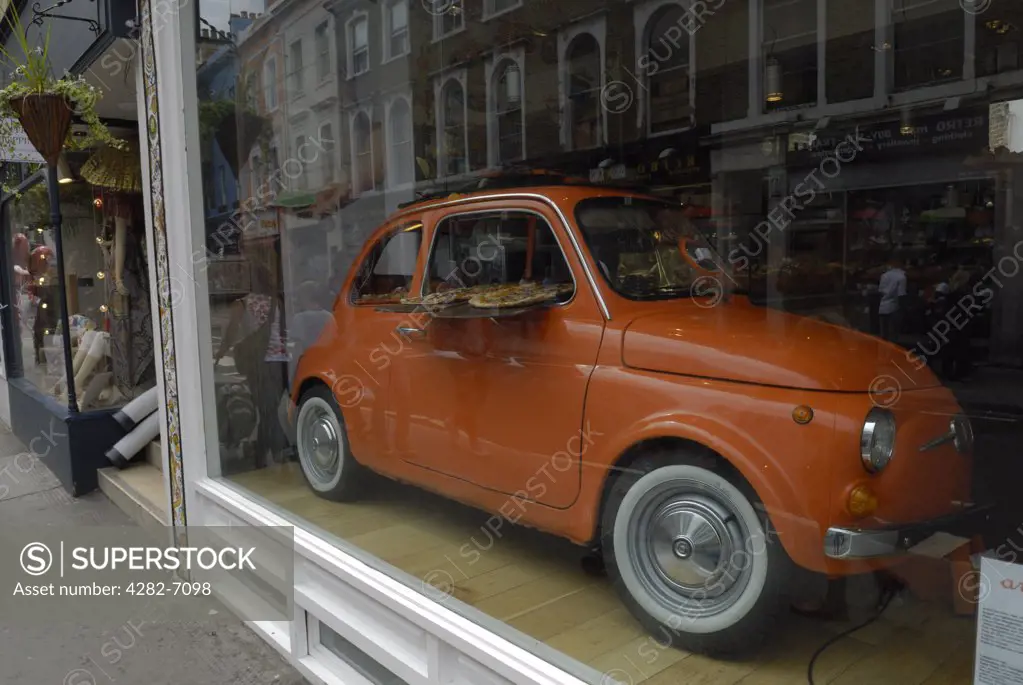 England, London, Notting Hill. An iconic Fiat 500 car used to display pizzas in the window of a pizza restaurant in Notting Hill.