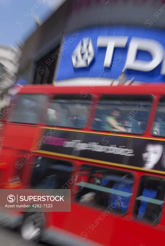 England, London, Piccadilly Circus. A red London double decker bus going past advertisements in Piccadilly Circus.