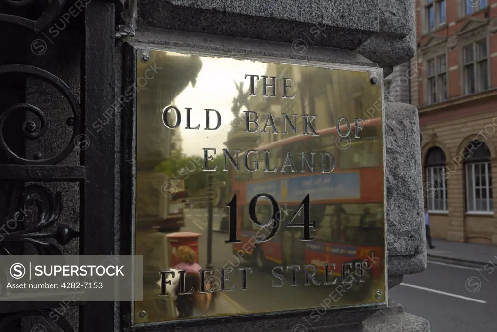 England, London, Fleet Street. A red double decker bus reflected in a name plate for The Old Bank of England pub, situated in the former Law Courts' branch of the Bank of England.