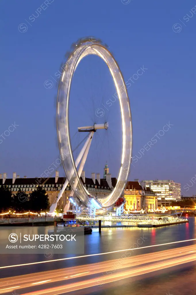 England, London, South Bank. A view across the Thames to an illuminated London Eye at dusk.
