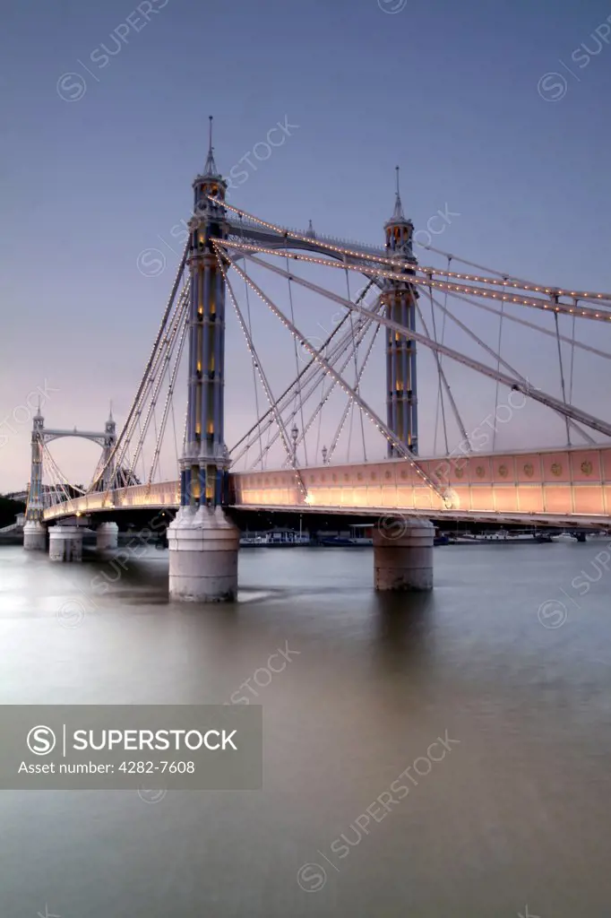England, London, Battersea. A view from the banks of the River Thames to the Albert Bridge at dusk.