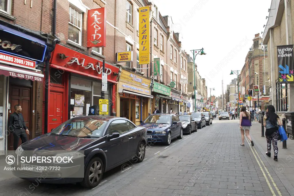 England, London, Brick Lane. Cars parked outside shops, restaurants and cafes in Brick Lane.