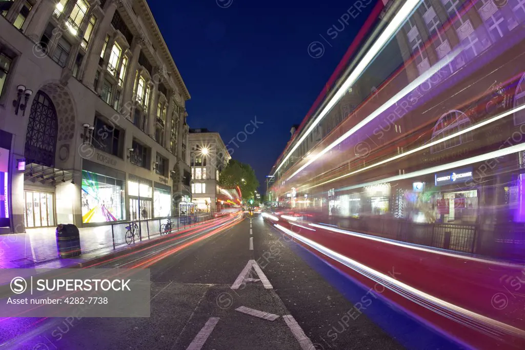 England, London, Oxford Street. Light trails from a car and double decker bus travelling along Oxford Street at night.