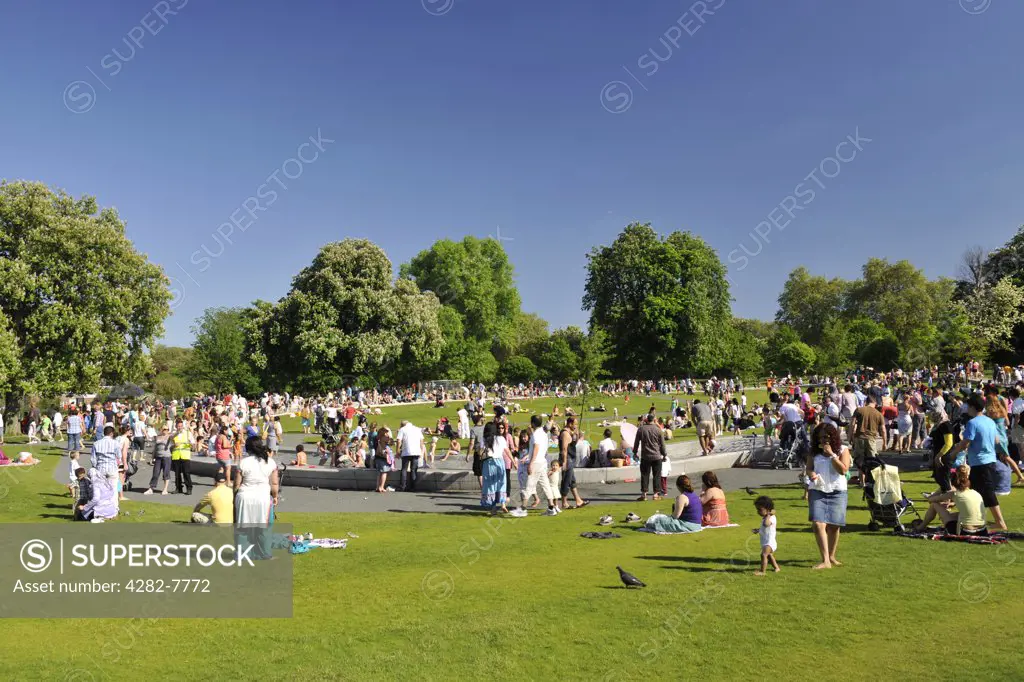 England, London, Hyde Park. Crowds of people enjoying the Diana, Princess of Wales Memorial Fountain in Hyde Park on a hot summers day.