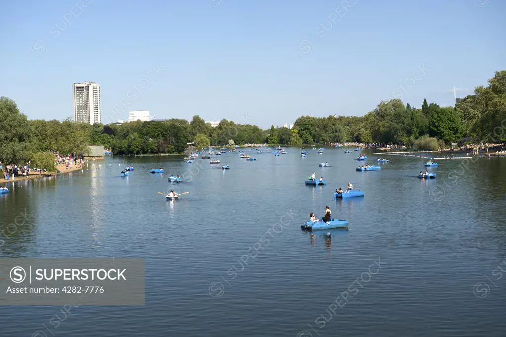 England, London, Hyde Park. People boating in pedalos and rowing boats on the Serpentine in Hyde Park on a hot summers day.