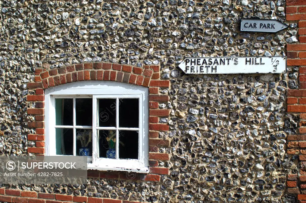England, Buckinghamshire, Frieth. Traditional brick and flint cottage with signposts in Frieth. Frieth lies on top of  'Frieth Hill', which is part of the chalk escarpments of the Chiltern Hills.