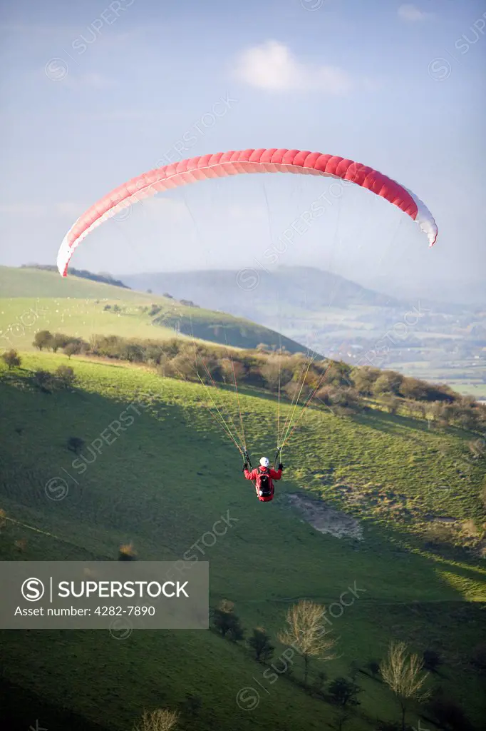 England, East Sussex, Sussex Downs. A lone paraglider soars above Devils Dyke on the East Sussex Downs.