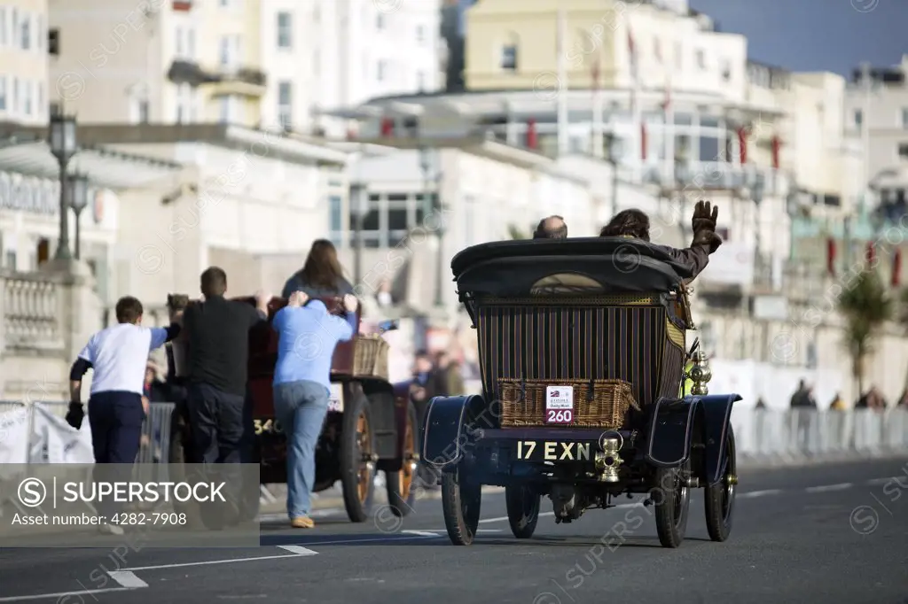 England, City of Brighton and Hove, Brighton. A car being pushed along as another overtakes in the 2008 London to Brighton Veteran Car Run.