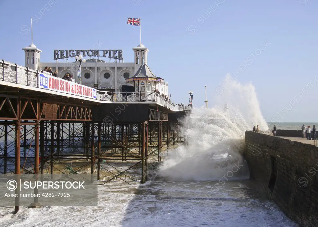 England, City of Brighton and Hove, Brighton. Waves crash over a jettty next to Brightons Pavillion pier.