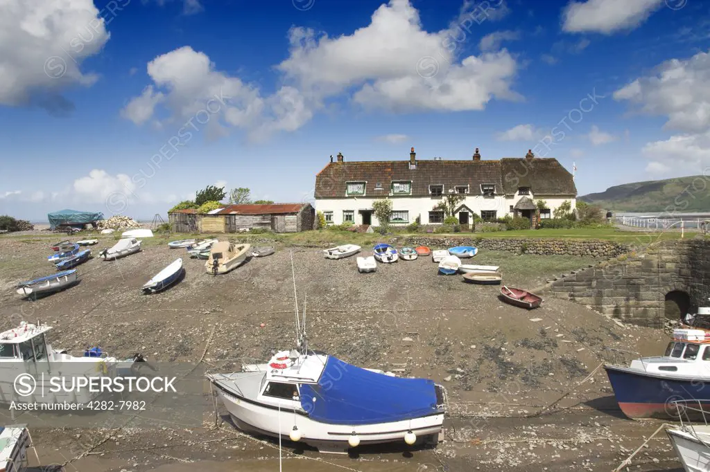 England, Somerset, Porlock Weir. Thatched coastal cottages and boats at the small tidal harbour of Porlock Weir.