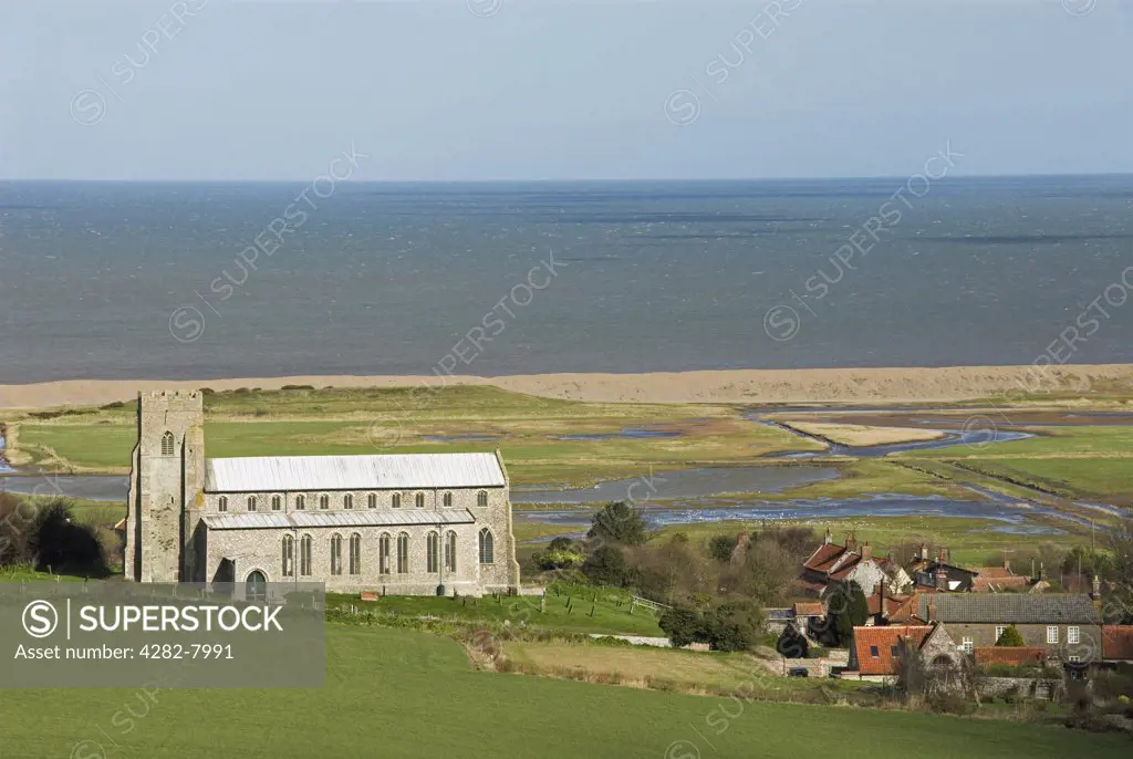 England, Norfolk, Salthouse. Salthouse church and village showing coastal freshmarsh and sea wall in the distance.