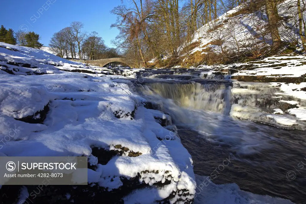 England, North Yorkshire, Stainforth. Stainforth Force, a waterfall on the River Ribble and 17th century Packhorse Bridge in winter.