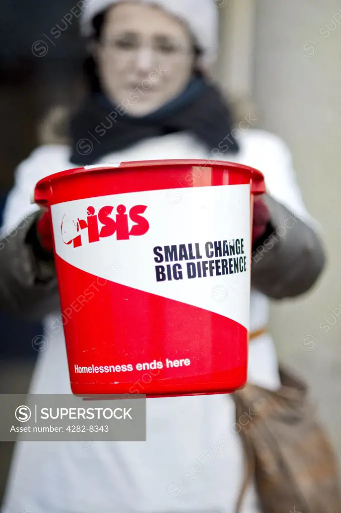 England, London. A woman collecting change in a bucket for Crisis at Christmas, the national charity for single homeless people.
