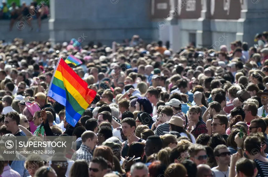 England, London. A Gay Pride flag held up amidst a large crowd of people at the annual Pride London celebrations.