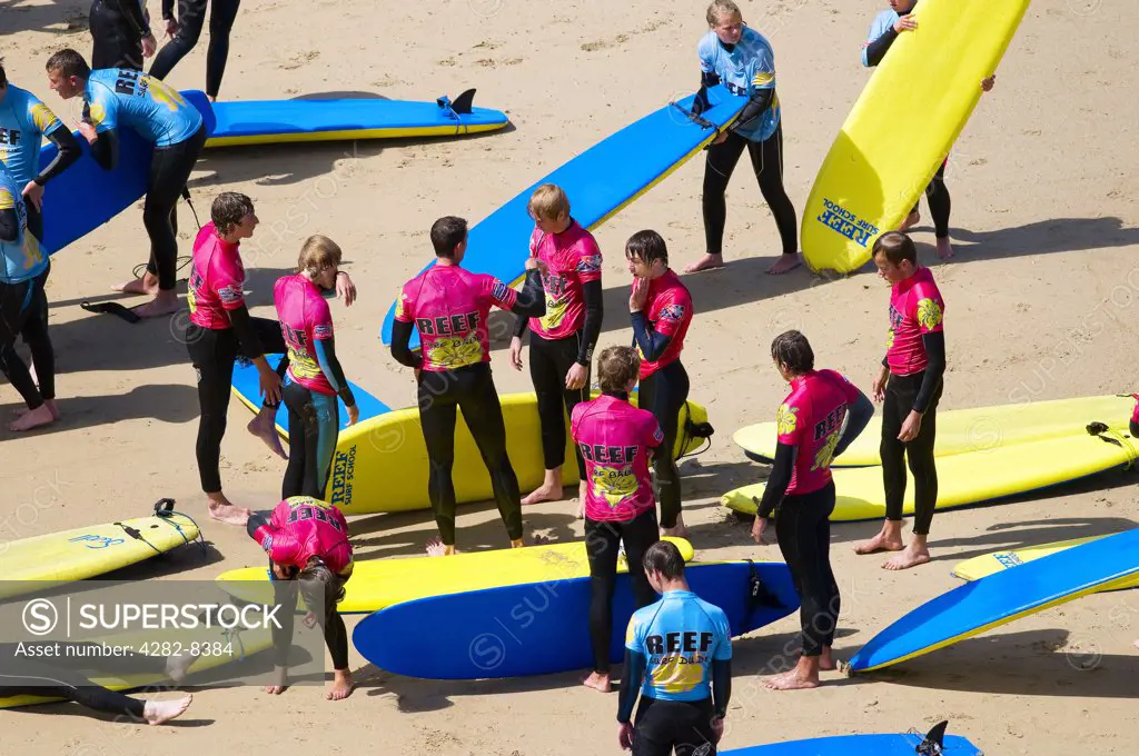 England, Cornwall, Newquay. Young people receiving instructions at a surf school on a beach in Newquay.