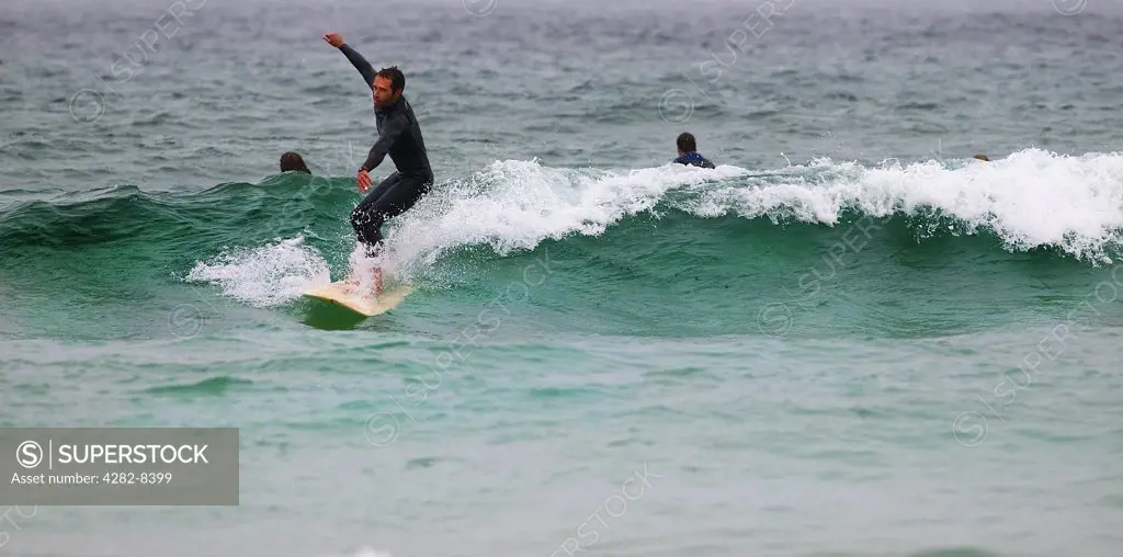 England, Cornwall, Sennen. A surfer riding the waves at Sennen.