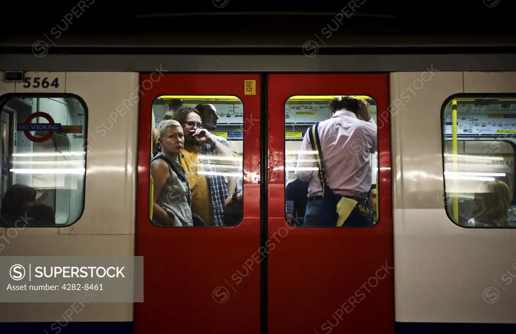 England, London. Commuters standing on board a London Underground tube train.