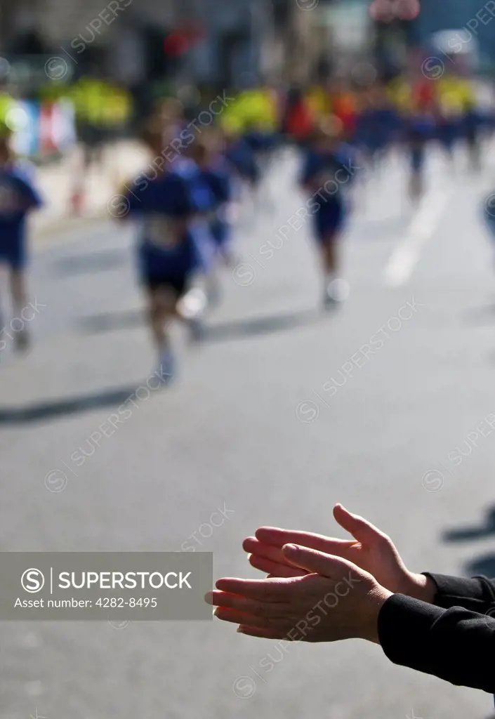 England, London. A spectator applauding runners taking part in the London Marathon.