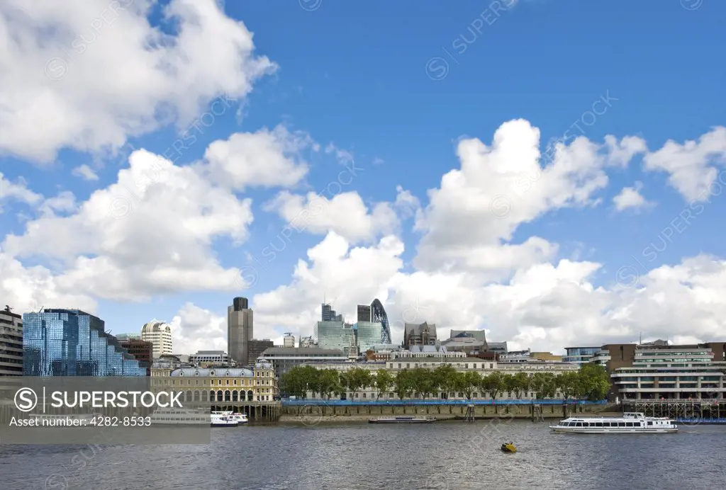 England, London, City of London. A sightseeing cruise boat travelling along the River Thames past some iconic London landmarks on the City of London skyline.