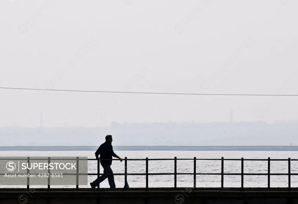 England, Essex, Canvey Island. The silhouette of a man walking along a gantry.