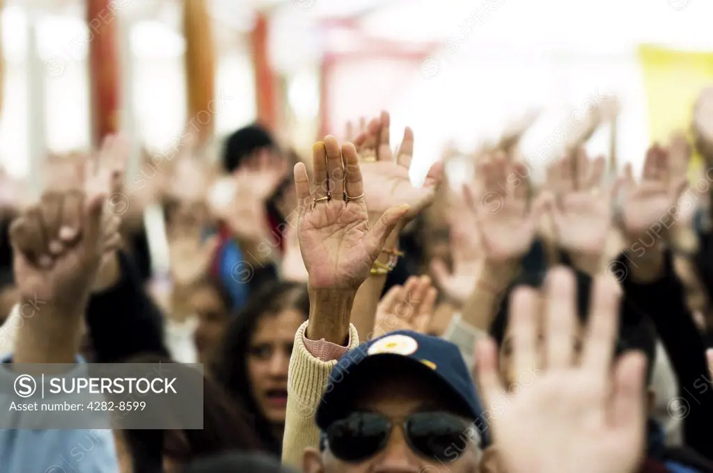 England, Essex, Southend-on-Sea. Raised hands of devotees attending a Ganesh festival.