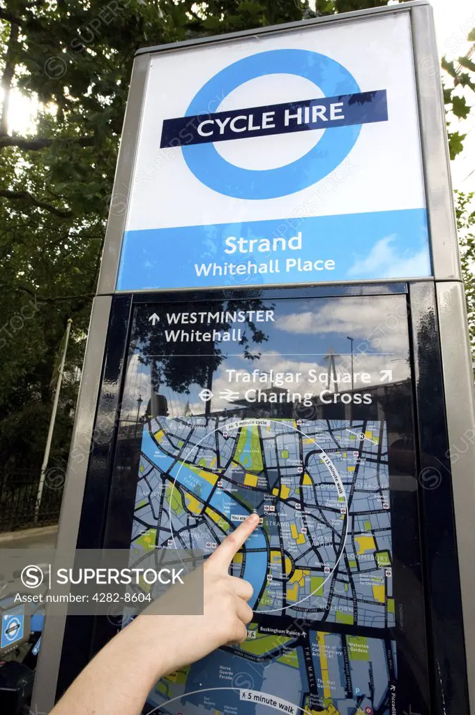 England, London, Westminster. Close-up of a persons hand pointing out their location on a map at a terminal of a Barclays Cycle Hire docking station.