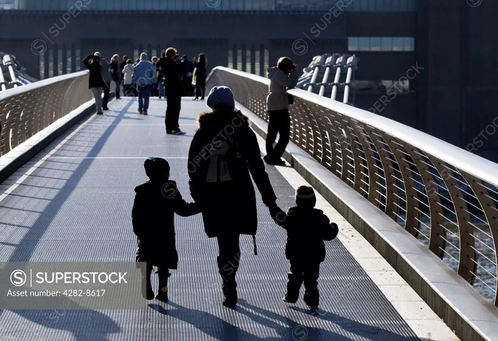 England, London, Millennium Bridge. A mother and children crossing the Millennium Bridge over the River Thames.