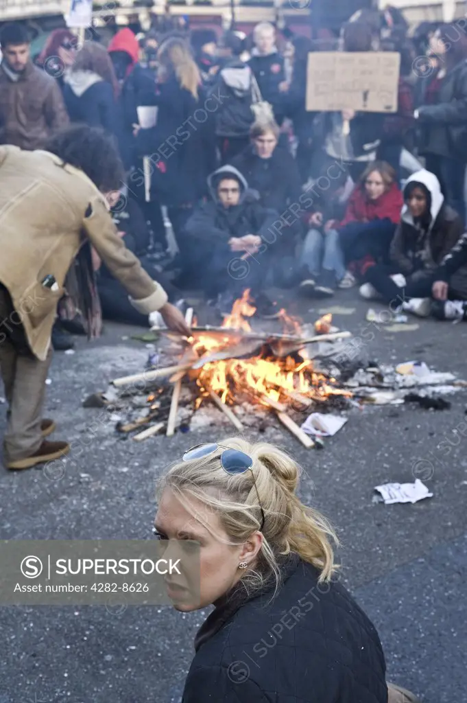 England, London. Students sitting around a bonfire in a street during a student demonstration.