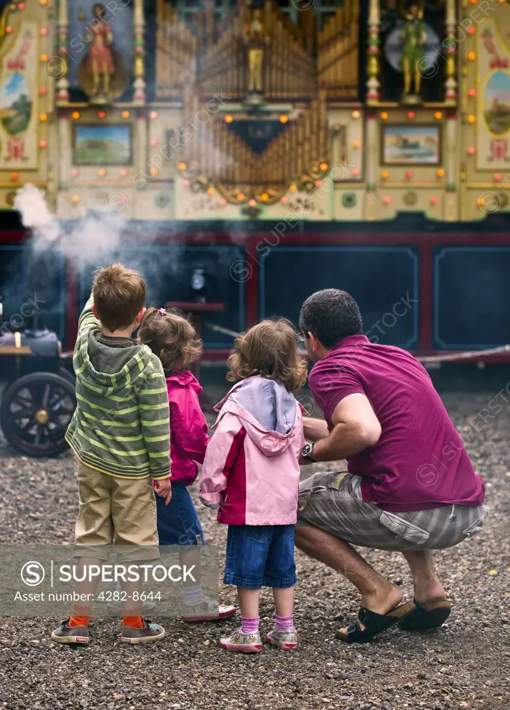 England, Essex, Audley End. Father and children looking at a steam organ at the Audley End Steam Gala 2011.