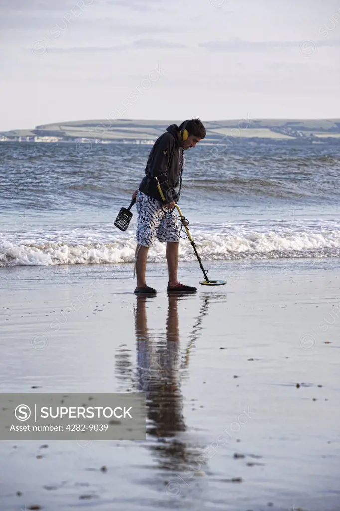 England, Dorset, Bournemouth. A man metal detecting on the seashore at Bournemouth.
