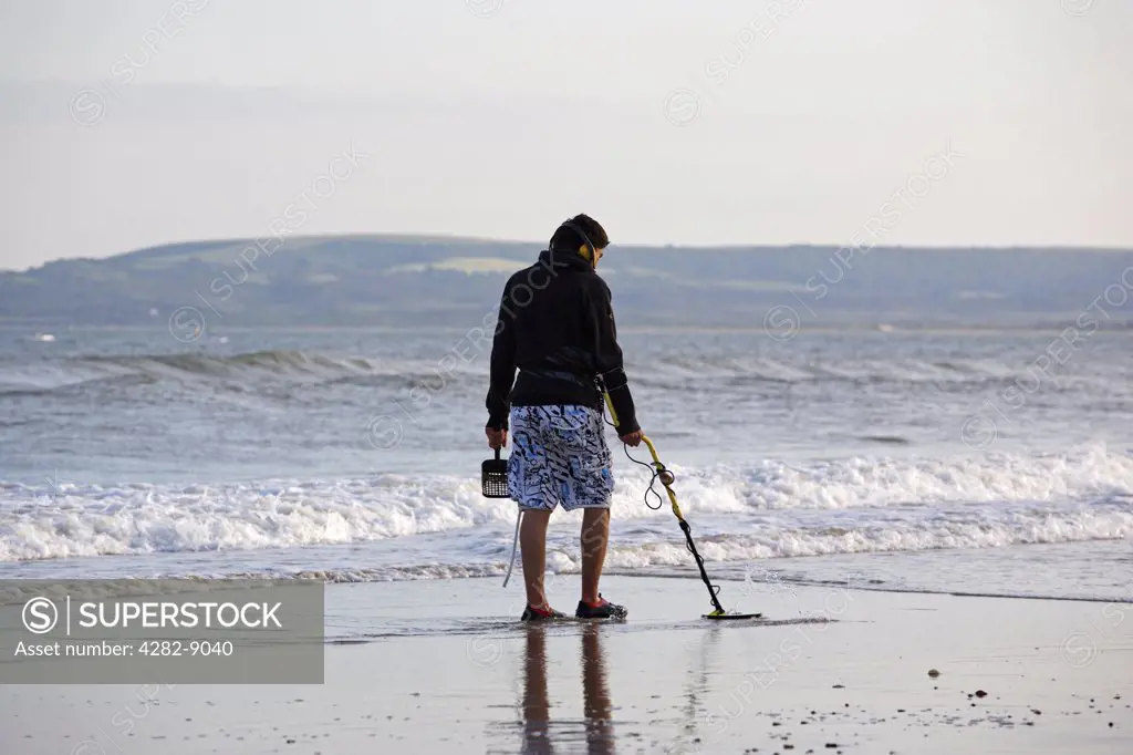 England, Dorset, Bournemouth. A man metal detecting on the seashore at Bournemouth.