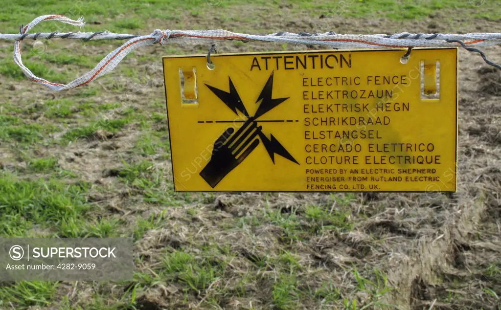 England, Warwickshire. Attention sign hanging from an electric fence.