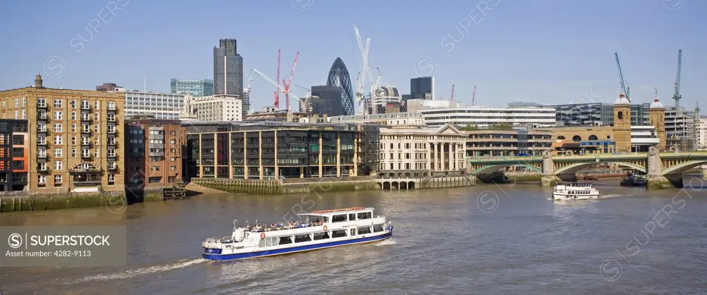 England, London, Southwark Bridge. A panoramic view of a sightseeing boat travelling along the River Thames heading towards Southwark Bridge and the City of London.