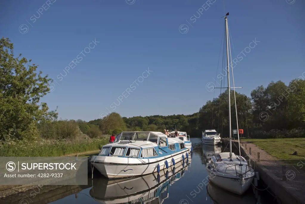 England, Norfolk, Near Thorpe St Andrew. People relaxing on a boating holiday on the River Yare on the Norfolk Broads.