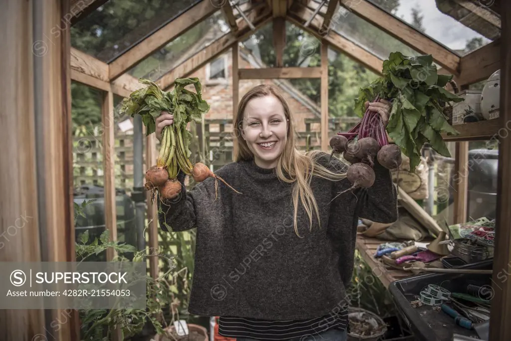A young female gardener works in her greenhouse.