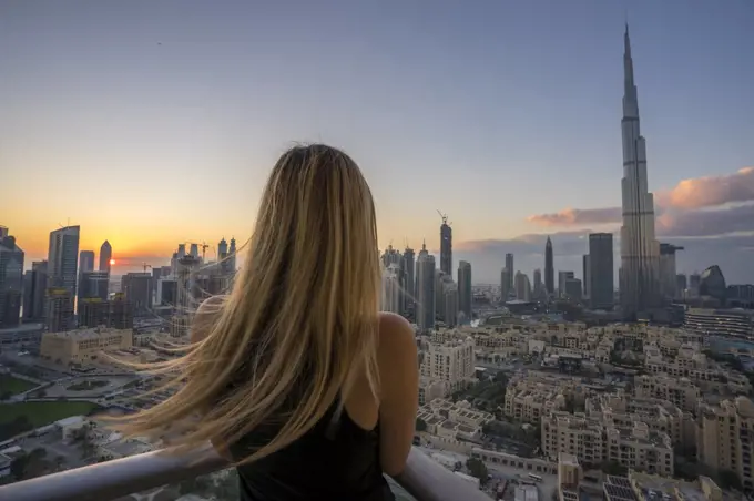A woman peers off the balcony of her apartment in Dubai.