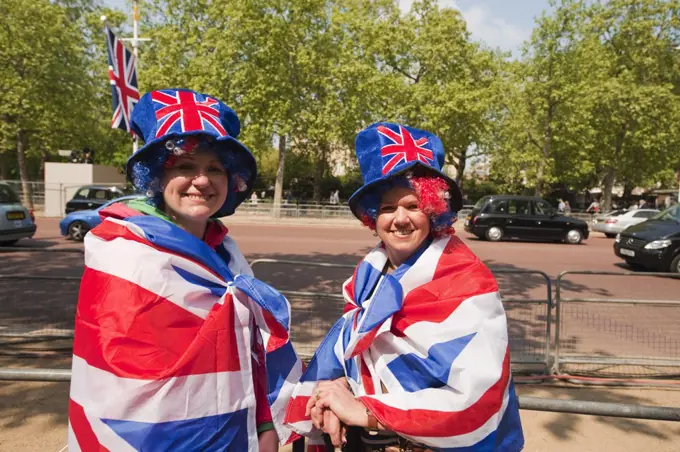 England, London, The Mall. Two happy Royal Wedding spectators on The Mall a day before the big event in central London, dressed in union flags.