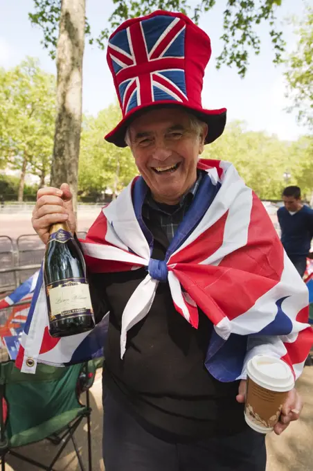 England, London, The Mall. A happy Royal Wedding spectator on The Mall in central London a day before the big event holding a bottle of Prince William Champagne.