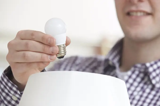 Man Putting Low Energy LED Lightbulb Into Lamp At Home