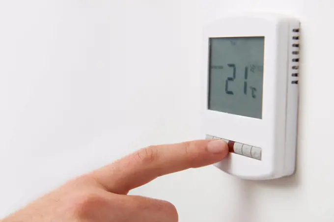 Close Up Of Hand Adjusting Digital Central Heating Thermostat