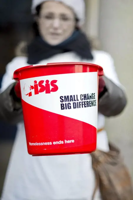 England, London. A woman collecting change in a bucket for Crisis at Christmas, the national charity for single homeless people.